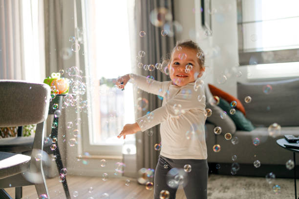 istock Happy little girl is playing with soap bubbles 1902428775