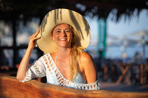 Carefree woman sitting in a beach bar and looking away
