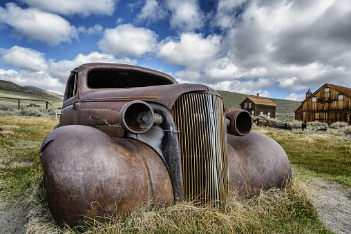 Rusted abandoned car in front of stone house at Silverton, Australia