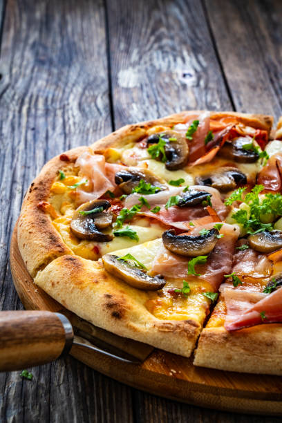 istock Pizza speck with ham, mozzarella cheese and white mushrooms on wooden table 1902452824