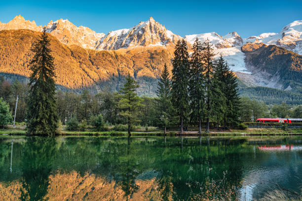 istock Lac des Gaillands with train passing and Mont Blanc massif reflection in the sunset at Chamonix, France 1902469155
