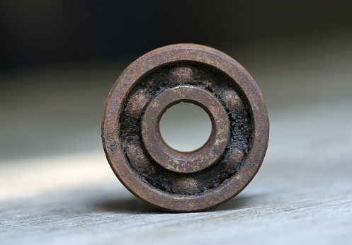 old and rusty ball bearing with grease stain. rusty bull bearing on wood table . close up  . corrosion of steel