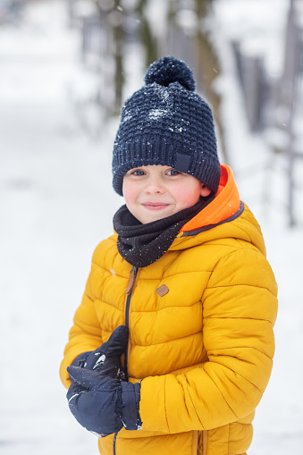 Winter games outdoors. Active outdoors leisure with children in winter. Kid boy walking and playing in warm clothes, winter time