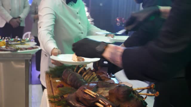 sliced pieces of grilled salmon fillet are placed on plates in the hands of a restaurant waiter.