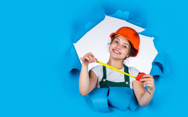 istock cheerful child laborer using building uniform and tape measure, copy space, labor day 1902613977