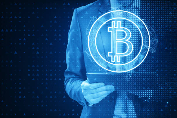 istock Close up of pixel businessman using tablet with abstract bitcoin hologram on blue background. Cryptocurrency and finance concept. 1902621246