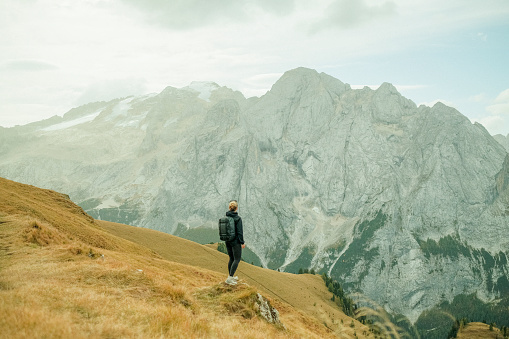 Young woman backpacker  hikes up path in mountains