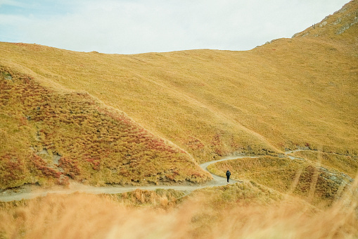 Young woman backpacker  hikes up path in mountains