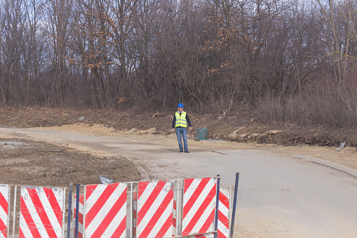 Mature adult inspector controlling quality of works at road construction site using tablet