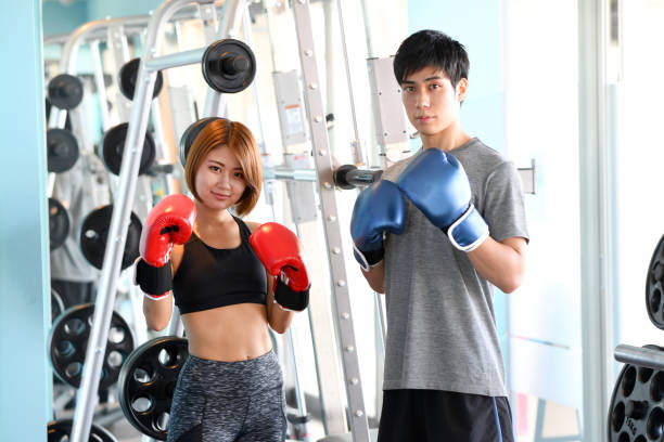 Asian woman and man doing fighting pose at martial arts gym Asian woman and man doing fighting pose at martial arts gym boxercise stock pictures, royalty-free photos & images