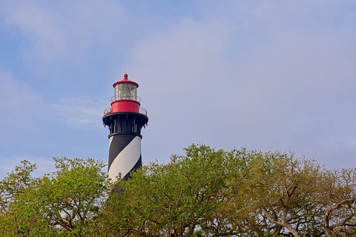 The Saint Augustine lighthouse stands above the native trees. The 1874 lighthouse stands near where the Matanzas river flows into the Atlantic near the Saint Augustine Inlet.