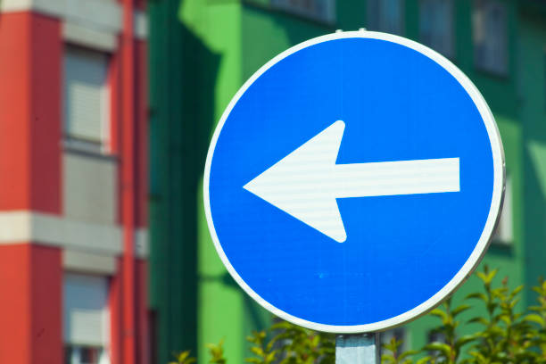 Traffic arrow sign, urban road sign, apartment building facades in the background. Galicia, Spain.