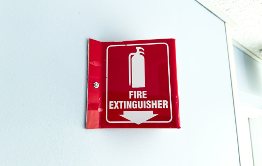 Red and white fire extinguisher sign on wall indicating emergency safety equipment presence