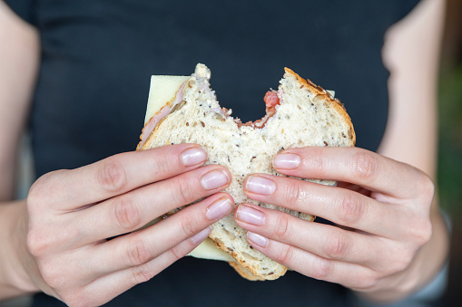 A woman's hand eats a sandwich with various healthy ingredients. Eating sandwiches. High quality photo