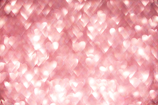 Pink hearts, sparkling bokeh, abstract defocused background for Valentine's Day.