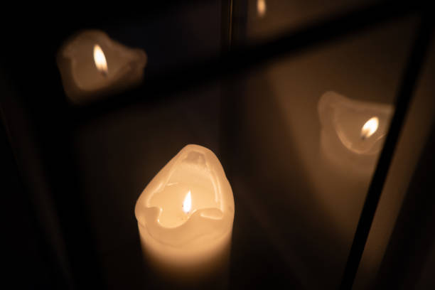 Single lit pillar candle reflecting in glass panels on lantern.