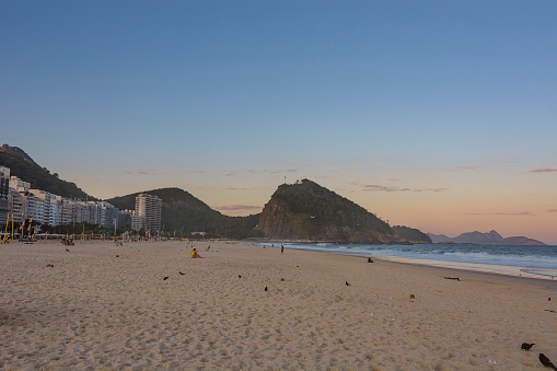 Rio de Janeiro, Brasil. 05.22.22. Leme beach and Ponta do Leme mountain at sunset. Duque de Caxias Fort at the top.