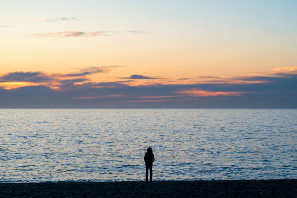 Calahonda, Granada, Spain. 12/20/2023.  Person walking along the beach in the town of Calahonda, Granada, at sunrise.
