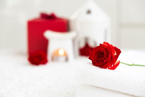 White towels with red rose and candles. Spa therapy, massage salon, romantic relaxation concept. Valentine`s Day feeling: love, care, romance, treatment. Selflove. Copy space.