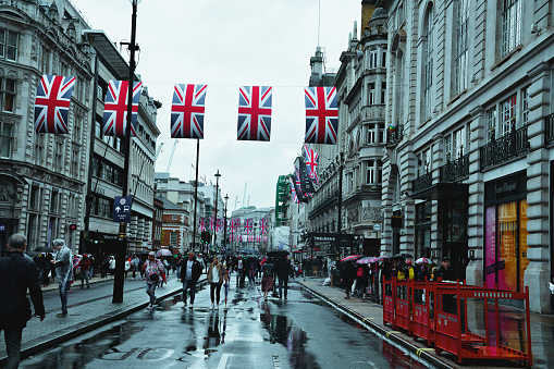 Looking east from Charing Cross, rows of British flag bunting strung between buildings on major thoroughfare linking Westminster and London.