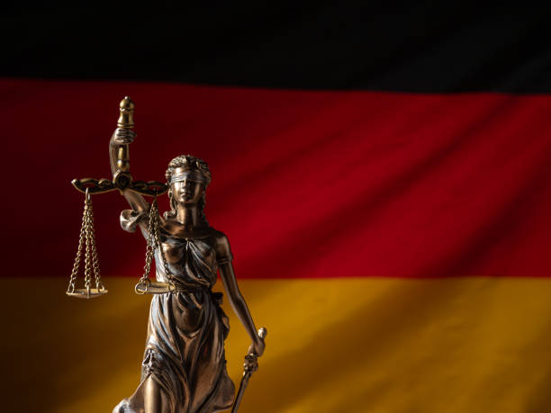 bronzene justizstatue mit der deutschen flagge im hintergrund. - civil rights stock-fotos und bilder