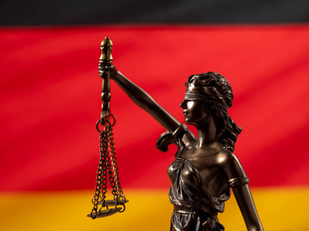 bronzene justizstatue mit der deutschen flagge im hintergrund. - civil rights stock-fotos und bilder