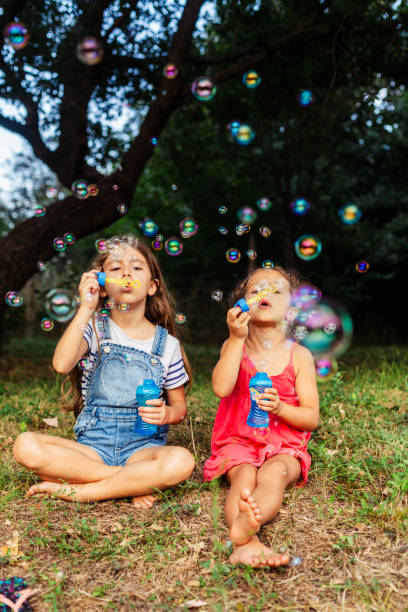 istock Two girls having fun blowing soap bubbles in nature 1902935957
