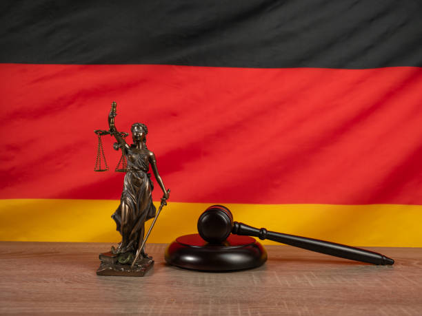 bronzestatue der gerechtigkeit und richterhammer vor dem hintergrund der deutschen flagge. - civil rights stock-fotos und bilder