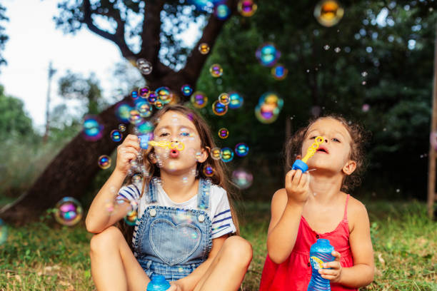 istock Two girls having fun blowing soap bubbles in nature 1902936488