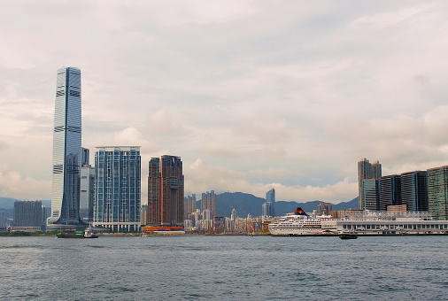 This photograph shows a portion of an area in Hong Kong known as West Kowloon. Towards the left side stands a famous skyscraper known as the International Commerce Centre (ICC), and on the right side, is what appears to be a cruise ship for tourists. The scene was photographed during September of 2010.