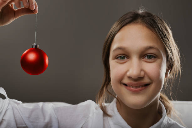 istock Girl's smile brightens while holding Christmas ornament 1902952803