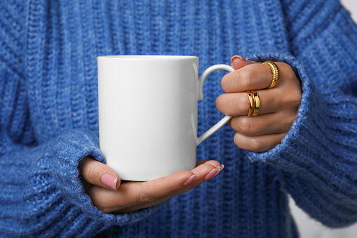 Woman holding white mug, closeup. Mockup for design