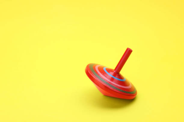 istock One bright spinning top on yellow background, space for text. Toy whirligig 1902990148