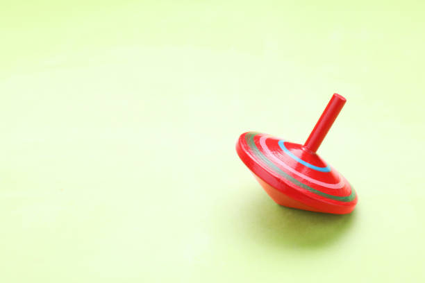istock One bright spinning top on light green background, space for text. Toy whirligig 1902990151