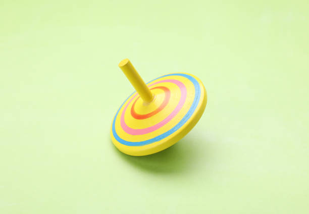 istock One bright spinning top on light green background. Toy whirligig 1902990153