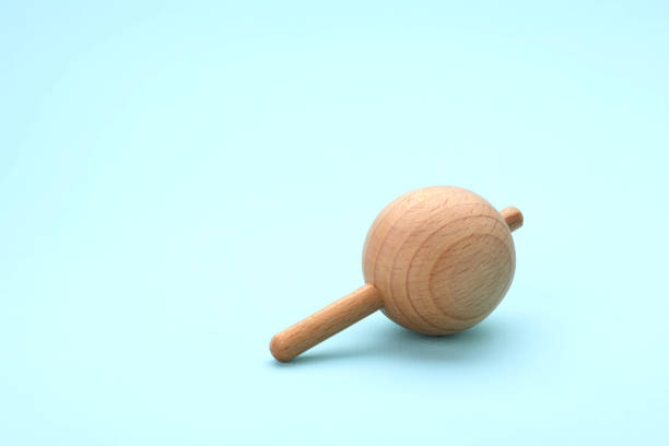 istock One wooden spinning top on light blue background, space for text. Toy whirligig 1902990157