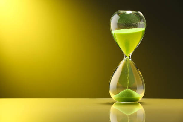 istock Hourglass with light green flowing sand on table against color background. Space for text 1902990158