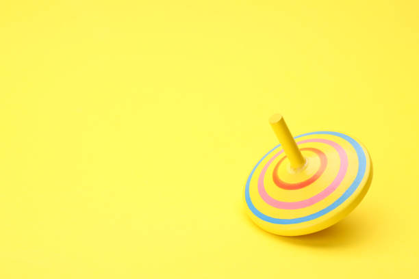 istock One bright spinning top on yellow background, space for text. Toy whirligig 1902990669