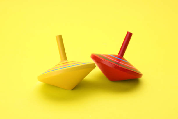istock Two bright spinning tops on yellow background. Toy whirligig 1902990670