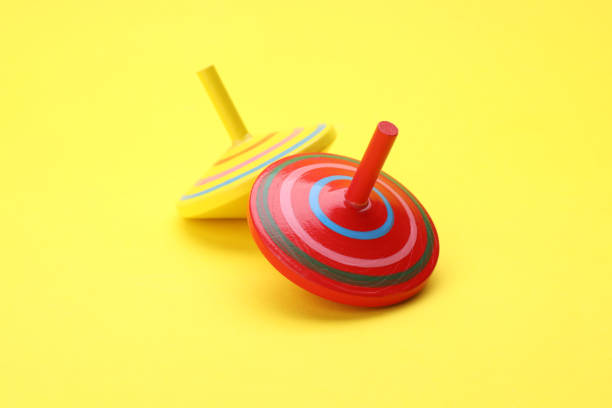 istock Two bright spinning tops on yellow background. Toy whirligig 1902990672