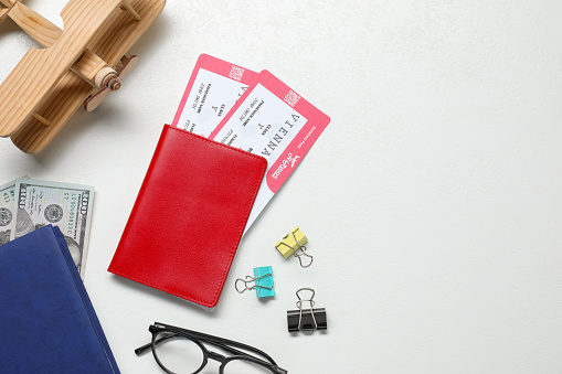 Flat lay composition with tickets, passport and wooden model of plane on white table, space for text. Business trip