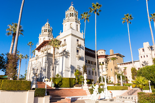 Hearst Castle, San Simeon, California - USA: Close-up view of Hearst Castle from the side. Towers, palm trees, sun, clear blue sky