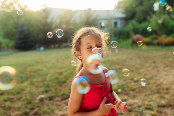 istock Little girl having fun playing with soap bubbles in nature 1903067675