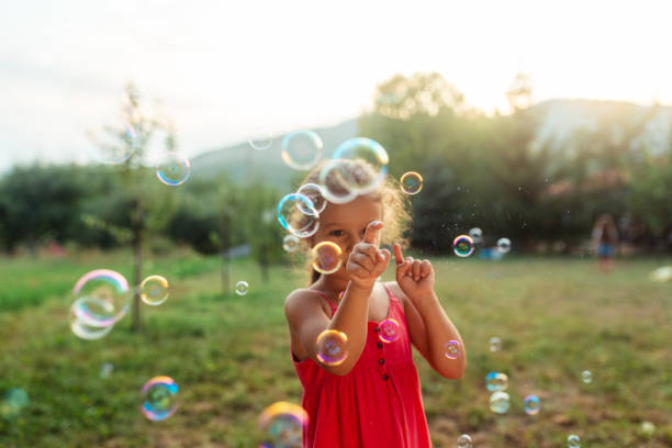 istock Little girl having fun playing with soap bubbles in nature 1903068699