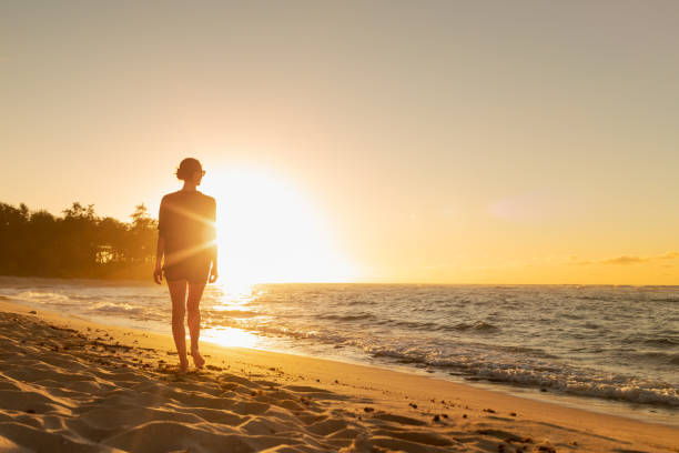 istock Woman walking on the beach at sunset. 1903073814