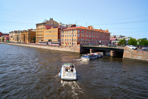 Cityscape of the street, bridge and water Fontanka river with recreational boats. Old residential multicolor buildings in the historical center of St. Petersburg, Russia.