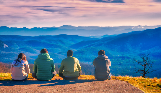 Canton, North Carolina, USA- December 28, 2023- Four friends relax and admire the scenery as they sit at the edge of the parking lot of The Cradle of Forestry Overlook along the Blue Ridge Parkway on a late December morning overlooking the Pisgah National Forest .