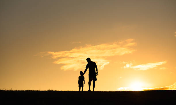 istock Father and son walking together at sunset. 1903132085