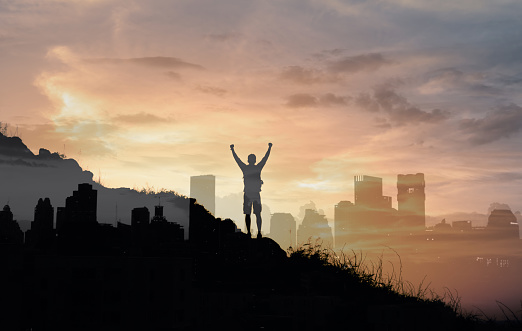 Strong, motivated, inspired man in the city with fist up to the sky. Double exposure.