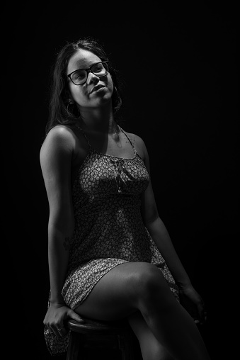 Black and white portrait of young woman with straight hair wearing glasses posing for photo.